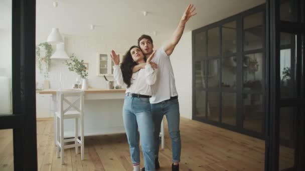 Os proprietários felizes planejam o interior da casa. Jovem casal abraçando em casa . — Vídeo de Stock