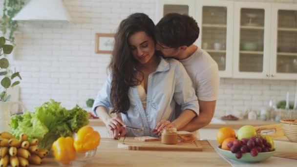 Portret van een gelukkig stel dat thuis kookt. jong getrouwd paar flirten in keuken. — Stockvideo