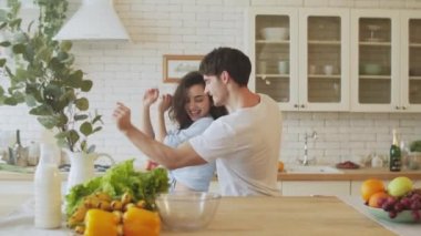 Mutfakta yavaş çekimde dans eden mutlu çift. İç çamaşırlı güzel kadın..