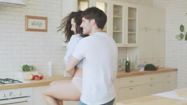 Junges Paar, das sich im Haus dreht. sexy Mann umarmt Frau in Dessous. — Stockvideo