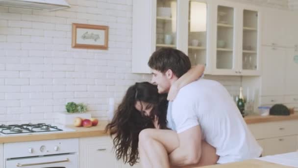 Молодая пара веселится в современном доме. Сексуальный мужчина играет с женщиной в нижнем белье — стоковое видео