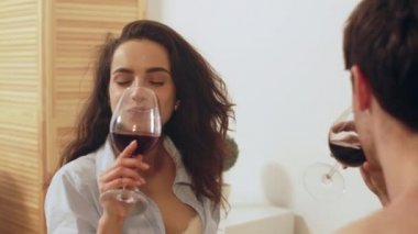 Mutlu çift evde ağır çekimde şarap içiyor. Şarap kadehli çift.