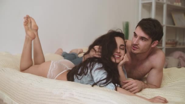Yatak odasında konuşan aşk çifti. Güzel erkek ve kadın yatakta yatıyor.. — Stok video