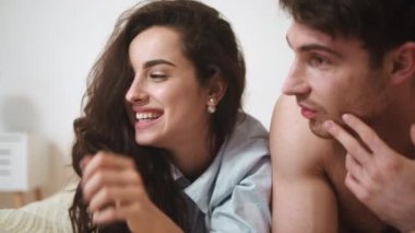 Yatakta yatan genç çifti yakından çek. Yatak odasında konuşan rahat bir çift.