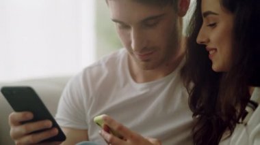 Mutlu çift evde cep telefonu kullanıyor. Çift görünümlü cep telefonları