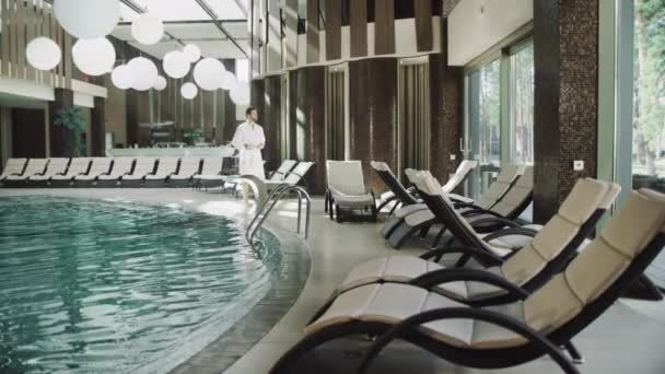 Bonito homem tirando roupas perto da piscina de água no hotel de luxo. — Vídeo de Stock
