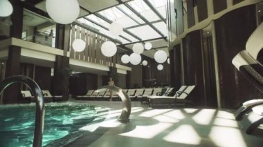 Güzel kız yüzme havuzunda yürüyor. Havuza bakan zarif bir kadın..