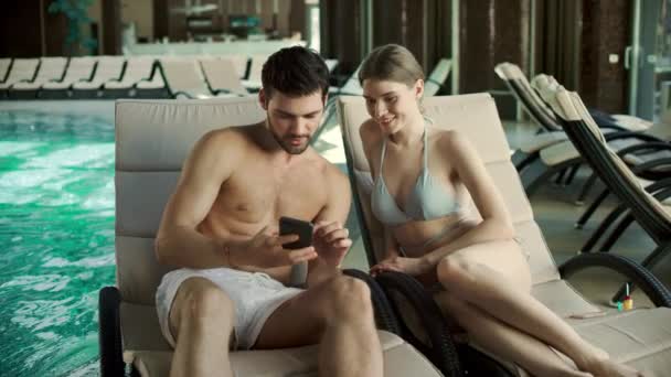 Couple proche couché sur des chaises longues avec des téléphones. Famille regarder la photo ensemble — Video