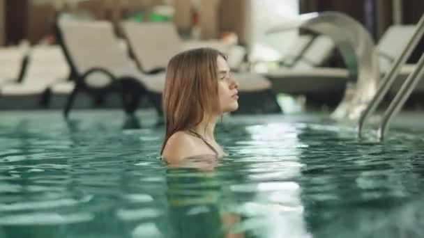 Close-up jonge vrouw zwemmen bij het zwembad. mooi meisje zwemmen in wellness cente — Stockvideo
