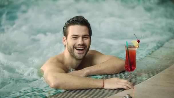 Primer plano alegre hombre divirtiéndose en bañera de hidromasaje. Sonriente hombre relajante piscina spa — Vídeo de stock