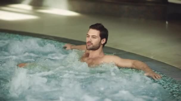 Uomo attraente a riposo vasca idromassaggio coperta. Uomo felice relax in piscina . — Video Stock