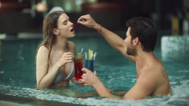 Ευτυχισμένο ζευγάρι που απολαμβάνει ποτά στο μπάνιο με υδρομασάζ. Νεαρή οικογένεια διασκεδάζει στην πισίνα — Αρχείο Βίντεο