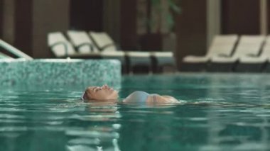 Otelde yüzen yakın plan kadın. Lüks oteldeki havuzda yüzen kadın.