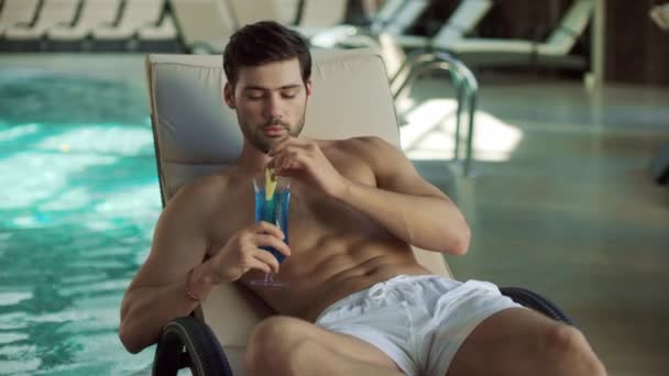 Portrait d'un homme buvant un cocktail près de la piscine. sexy guy flirt à chaise longue . — Video