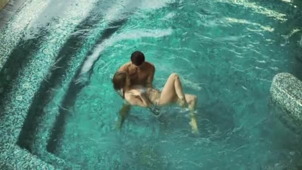 Пара купающихся в бассейне вместе. Над видом молодой семьи отдыха в бассейне. — стоковое видео