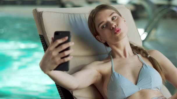 Primer plano chica haciendo selfie junto a la piscina en el spa. Chica en traje de baño disfrutando de vacaciones — Vídeos de Stock