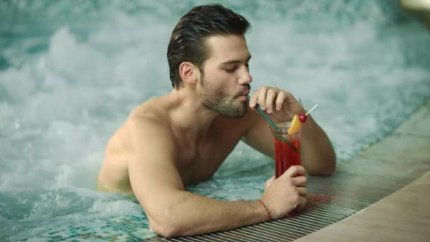 Primer plano sexy hombre bebiendo cóctel en la piscina de lujo. Guapo chico bebiendo alcohol — Vídeos de Stock