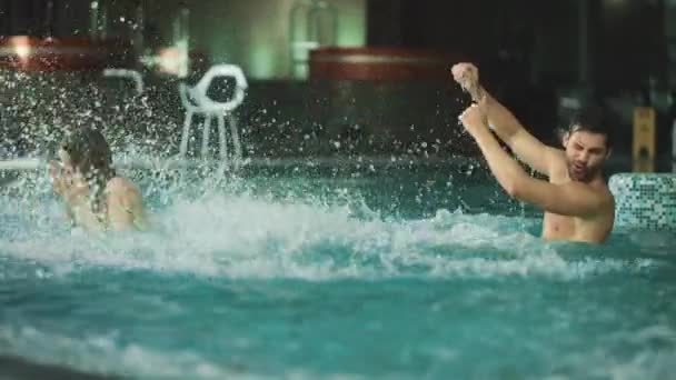 Happy couple splashing in pool together. Romantic couple having fun in pool — Stock Video