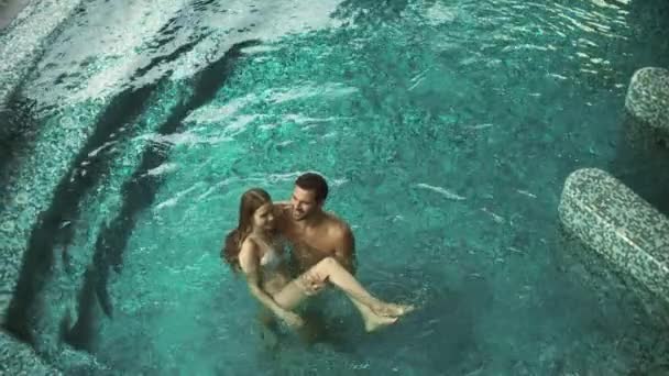 Acima vista atraente casal relaxante na piscina. Casal feliz desfrutando de piscina de luxo — Vídeo de Stock
