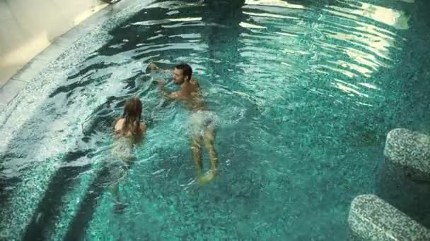 Ovanför utsikt över lyckliga par simning i poolen. Vackra par avkopplande i poolen — Stockvideo