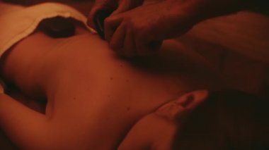 Yakından sıcak taşlarla rahatlayan güzel bir kadın. Erkek eller masajcı genç kız