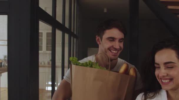 Pareja feliz trayendo comida saludable en paquetes juntos . — Vídeos de Stock