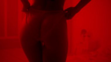 Karanlık odada seksi iç çamaşırlarıyla poz veren çıplak bir kız. Cinsel kadın kalçaları..