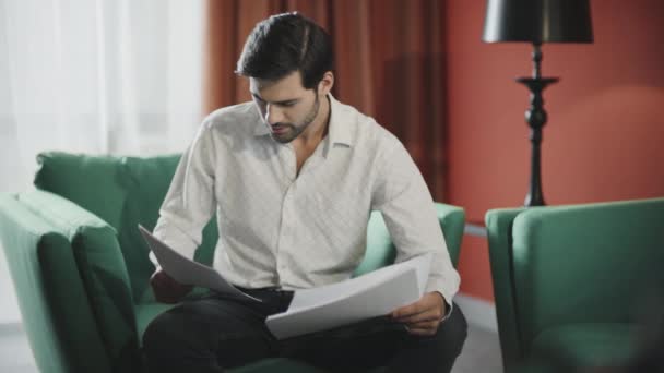 Konzentrierter Geschäftsmann, der im Hotel Dokumente liest. Selbstbewusster Mann überprüft Papiere — Stockvideo
