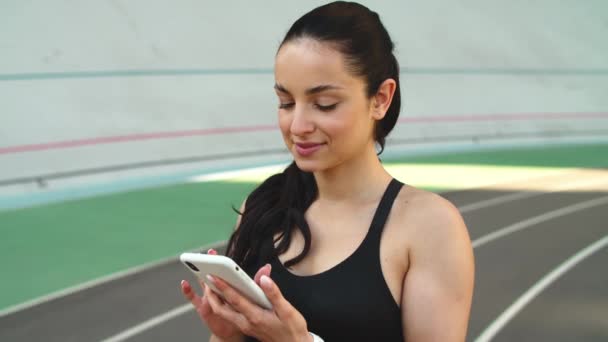 Γυμναστική γυναίκα ψάχνει smartphone σε εξωτερικούς χώρους. Γυναίκα δρομέας που χρησιμοποιεί τηλέφωνο — Αρχείο Βίντεο