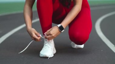 Spor salonundaki kadın, maraton için ayakkabılarını bağlıyor.