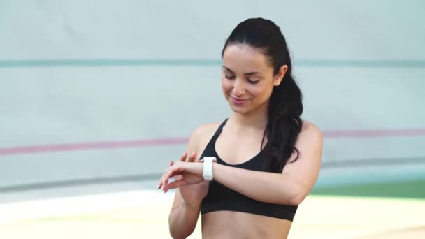 Chica del deporte comprobar los resultados en el reloj inteligente al aire libre. Mujer mirando reloj inteligente — Vídeo de stock