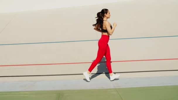 Mujer en forma trotando en pista de estadio. Corredor mujer corriendo en cámara lenta — Vídeo de stock