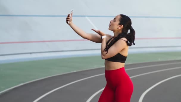 Futó nő csinál szelfi fotó a mobiltelefon a modern pályán — Stock videók