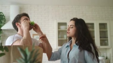 Genç evli çift ev mutfağında eğleniyor. Neşeli aile yemekle oynuyor.