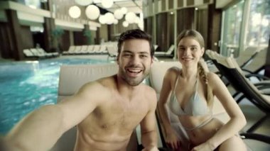 Yüzme havuzunun yanındaki selfie videosu için poz veren neşeli çiftin portresi..