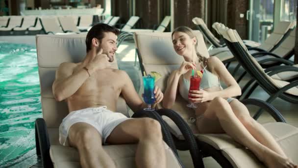 Un couple qui boit des cocktails dans des chaises longues. Homme et femme se relaxent ensemble — Video