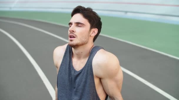 Coureur fatigué assis sur la piste du stade. Portrait de l'homme épuisé au repos — Video