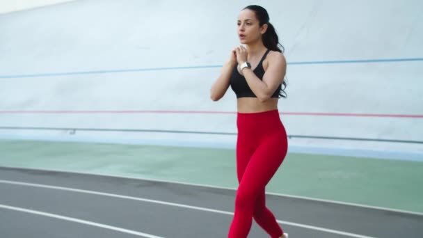 Jeune femme qui s'étire sur une piste sportive. Femme fitness faisant de l'exercice au stade — Video