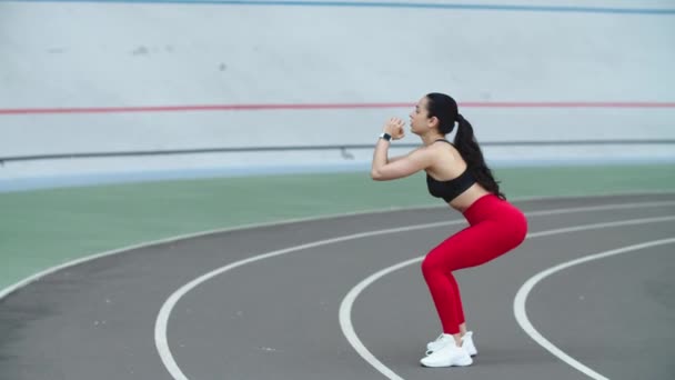 Kobieta ćwicząca w odzieży sportowej na torze. Dziewczyna rozciąganie na trening na torze — Wideo stockowe