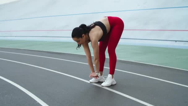 Corredor femenino preparándose para el entrenamiento en pista. Mujer haciendo ejercicio en pista al aire libre — Vídeos de Stock
