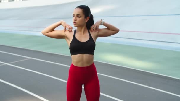 Kobieta z bliska rozciągająca się na stadionie sportowym. Dziewczyna ćwiczy na świeżym powietrzu na torze — Wideo stockowe