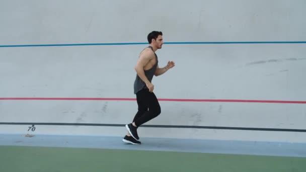 Sport man running in slow motion on track. Man runner jogging on athletics track — Stock Video