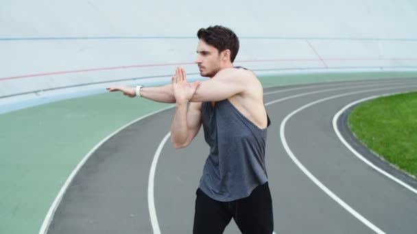 Az ember edzés előtt edz a sportstadionban. A futár bemelegít a stadionban. — Stock videók
