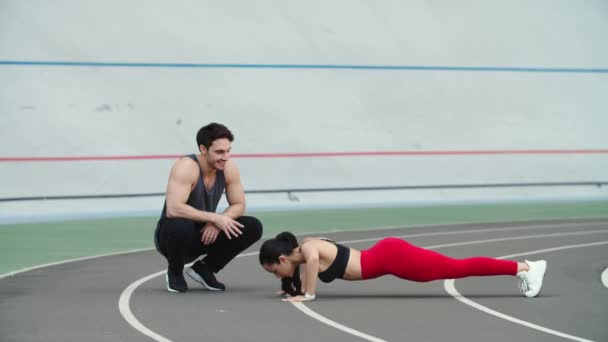 Par tränar tillsammans på rätt spår. Man och kvinna värmer upp på stadion — Stockvideo