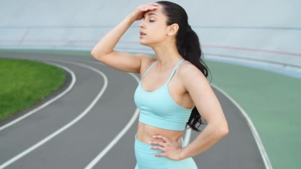 Corredor mulher atraente tendo descanso depois de correr treino na pista de corrida — Vídeo de Stock