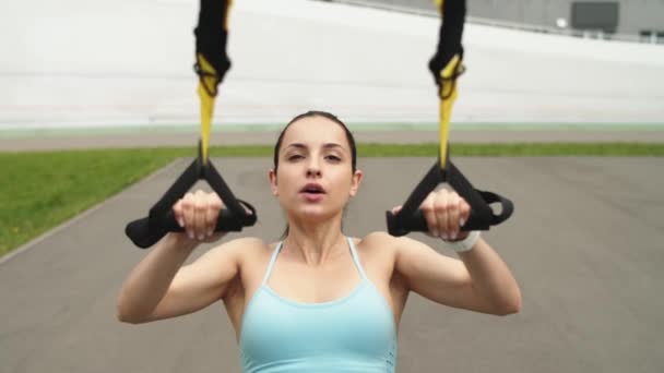 Närbild av fitness kvinna gör överkroppen övningar trx på stadion — Stockvideo