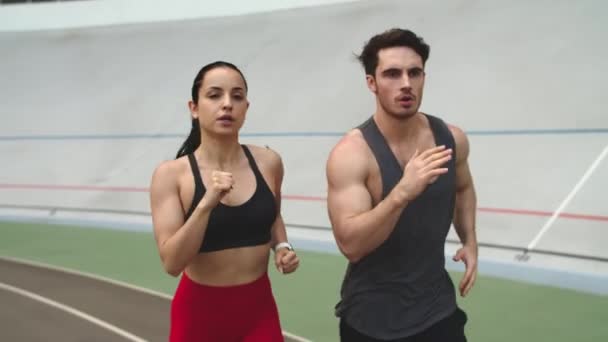 Casal de fitness a correr na pista de atletismo. Esporte casal formação em conjunto — Vídeo de Stock