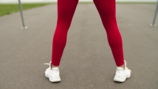 Mujer del deporte en cuclillas al aire libre en el estadio. Chica sexy haciendo ejercicio en ropa deportiva — Vídeo de stock