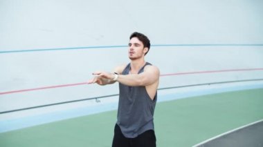 Sporcu ellerini piste uzatıyor. Erkek koşucu antrenmandan önce ısınıyor