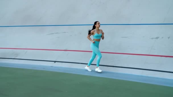Спортивная женщина бегает на спортивном стадионе. Бегунья в спортивной одежде — стоковое видео